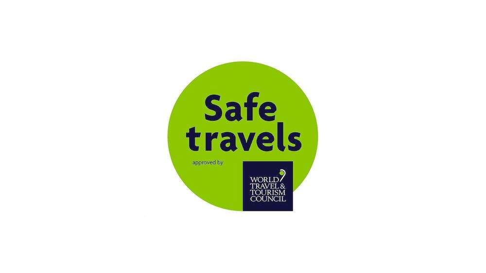 فندق مكارم أم القرى مكة المظهر الخارجي الصورة The image features a circular logo with a bright green background. In the center, the words "Safe travels" are prominently displayed in dark blue text. Below this phrase, it states "approved by" in smaller letters. At the bottom of the circle, there 