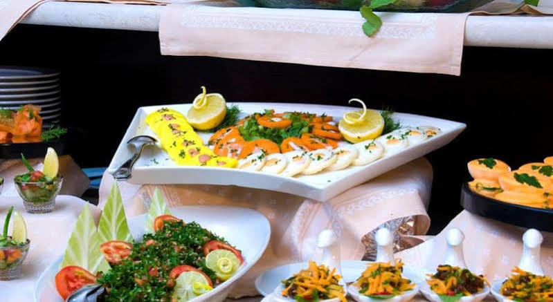 فندق مكارم أم القرى مكة المظهر الخارجي الصورة The photo showcases an elegantly arranged seafood platter. It features various types of sliced fish, likely including smoked salmon and other seafood options, garnished with fresh herbs and lemon slices. The platter is white and triangular in shape, 